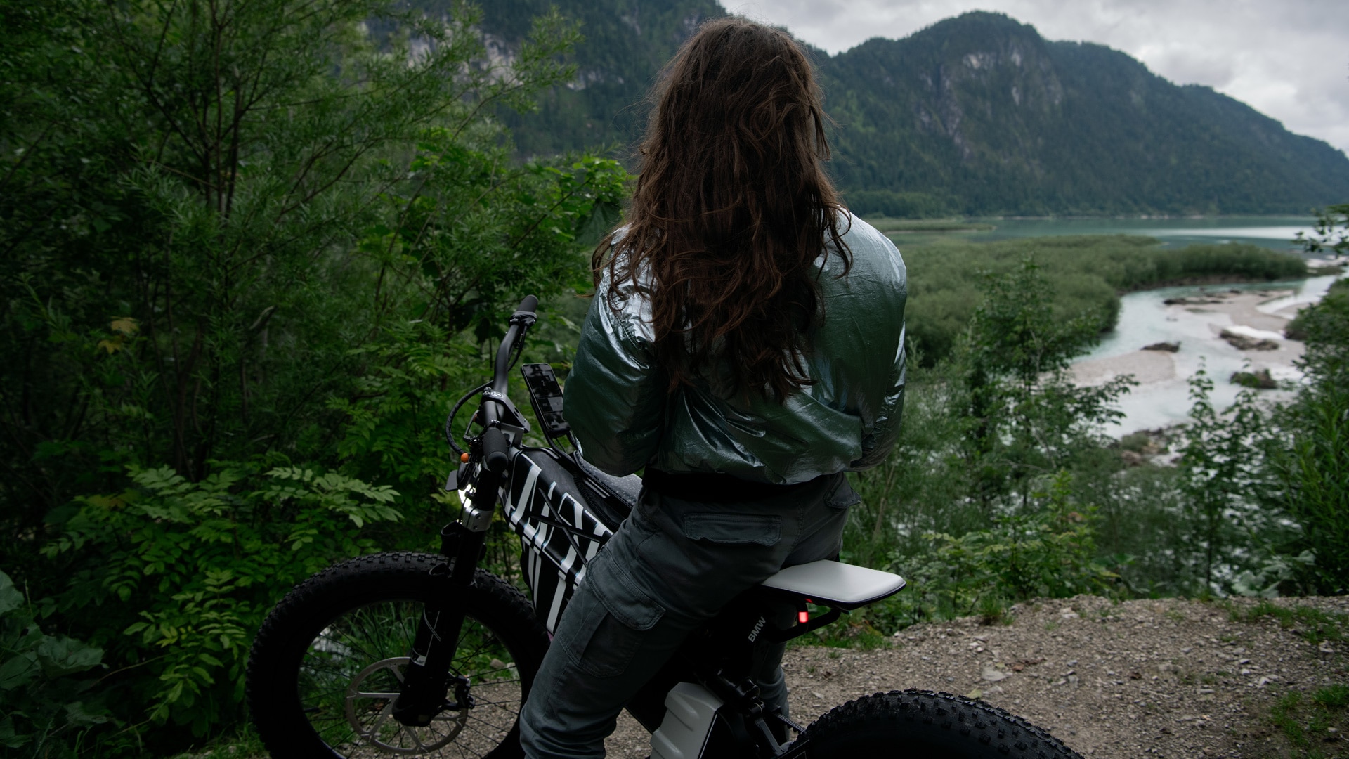 Mulher sentada na Vision AMBY com vista para um lago nas montanhas.